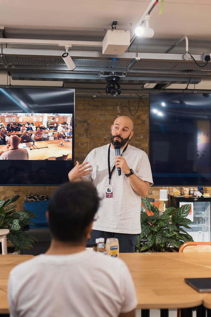 our-experience A speaker delivers a presentation in a modern office with an attentive audience.