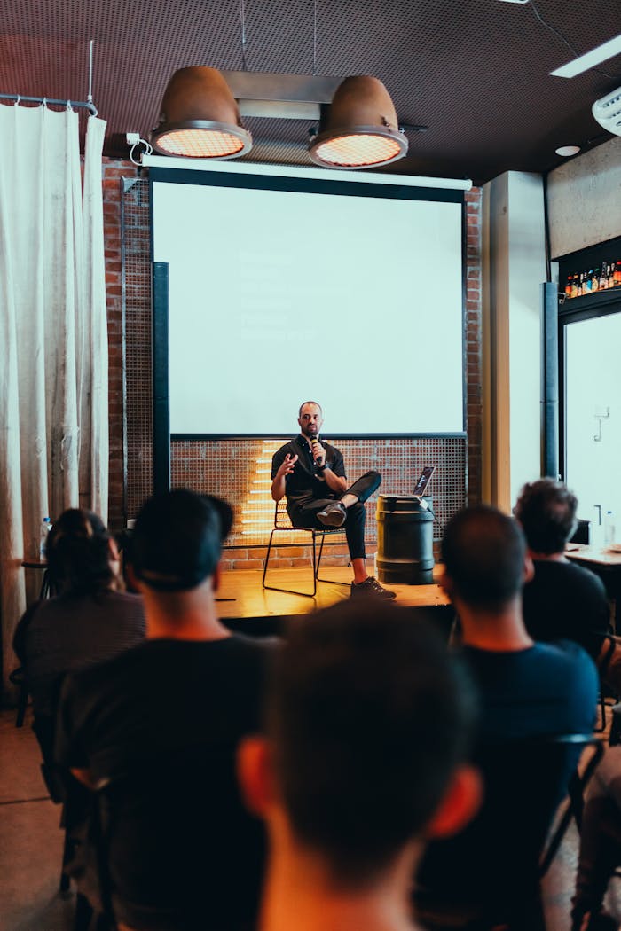 about-img Speaker engages an audience during a business seminar in a modern conference room.