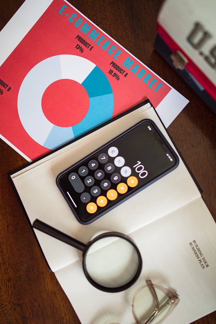 about-02 Overhead view of e-commerce chart with smartphone calculator and magnifying glass on a table.